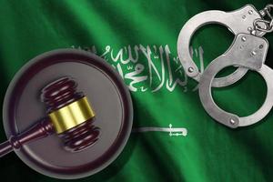 Saudi Arabia flag with judge mallet and handcuffs in dark room. Concept of criminal and punishment, background for judgement topics photo