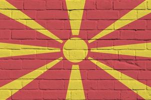 bandera de macedonia representada en colores de pintura en la pared de ladrillo antiguo. banner texturizado sobre fondo de mampostería de pared de ladrillo grande foto