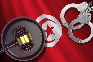 Tunisia flag with judge mallet and handcuffs in dark room. Concept of criminal and punishment, background for judgement topics photo