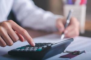 Business people use calculator to calculate documents, profit and loss statement review concept of company performance, effective tax deduction planning for individuals and companies paying tax rates photo
