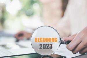 New Year 2023 Beginning Concept,man holding a magnifying glass,Finding new goals to develop and expand the business,future changes for success,direction and action for strategic planning photo