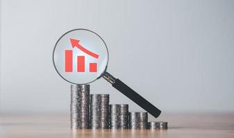 Stacks of coins, magnifying glass, and graph showing profit increase,business growth,concept of progress in development financial performance and investment,with business strategies for future goals photo
