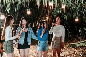 Group of female friends having fun holding bottles and drinking beer at the party photo