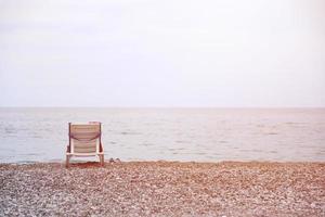 Chair on bank of pebbles with the sea and beach photo