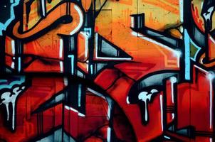 A fragment of detailed graffiti of a drawing made with aerosol paints on a wall of concrete tiles. Background image of street art in warm red color tones photo