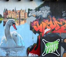 A fragment of detailed graffiti of a drawing made with aerosol paints on a wall of concrete tiles. Background image of street art with a huge white swan photo