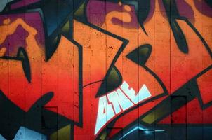 A fragment of detailed graffiti of a drawing made with aerosol paints on a wall of concrete tiles. Background image of street art in warm red color tones photo