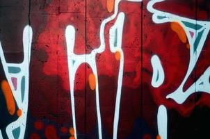 A fragment of detailed graffiti of a drawing made with aerosol paints on a wall of concrete tiles. Background image of street art in warm red color tones photo