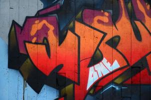 A fragment of detailed graffiti of a drawing made with aerosol paints on a wall of concrete tiles. Background image of street art in warm red color tones photo