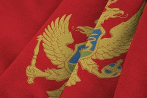 Montenegro flag with big folds waving close up under the studio light indoors. The official symbols and colors in banner photo