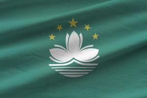 Macau flag with big folds waving close up under the studio light indoors. The official symbols and colors in banner photo