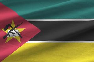 bandera de mozambique con grandes pliegues ondeando de cerca bajo la luz del estudio en el interior. los símbolos y colores oficiales en banner foto