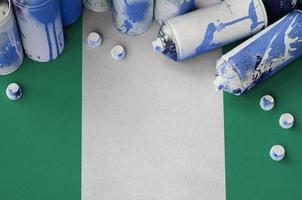 Nigeria flag and few used aerosol spray cans for graffiti painting. Street art culture concept photo