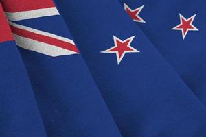 New Zealand flag with big folds waving close up under the studio light indoors. The official symbols and colors in banner photo