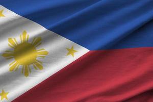 Philippines flag with big folds waving close up under the studio light indoors. The official symbols and colors in banner photo