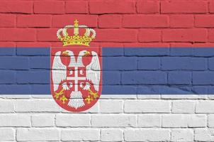 bandera de serbia representada en colores de pintura en la pared de ladrillo antiguo. banner texturizado sobre fondo de mampostería de pared de ladrillo grande foto