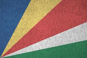 Seychelles flag depicted in bright paint colors on old relief plastering wall. Textured banner on rough background photo