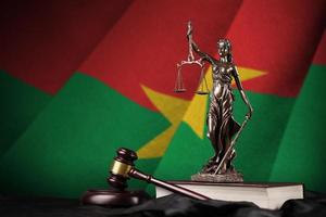 Burkina Faso flag with statue of lady justice, constitution and judge hammer on black drapery. Concept of judgement and guilt photo