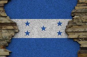 Honduras flag depicted in paint colors on old stone wall closeup. Textured banner on rock wall background photo