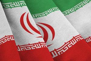 Iran flag with big folds waving close up under the studio light indoors. The official symbols and colors in banner photo