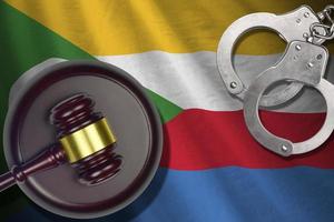 Comoros flag with judge mallet and handcuffs in dark room. Concept of criminal and punishment, background for judgement topics photo