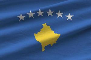 bandera de kosovo con grandes pliegues ondeando de cerca bajo la luz del estudio en el interior. los símbolos y colores oficiales en banner foto