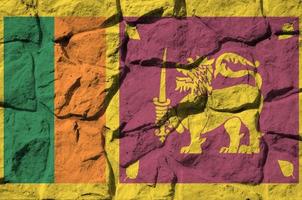 bandera de sri lanka representada en colores de pintura en el primer plano de la pared de piedra antigua. banner texturizado sobre fondo de pared de roca foto