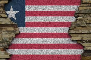 Liberia flag depicted in paint colors on old stone wall closeup. Textured banner on rock wall background photo