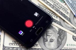 pantalla de teléfono inteligente con aplicación tiktok y muchos billetes de cien dólares. concepto de negocios y redes sociales foto