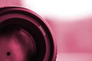 Fragment of a portrait lens for a modern SLR camera. A photograph of a wide-aperture lens with a focal length of 50mm Image toned in Viva Magenta, color of the year photo