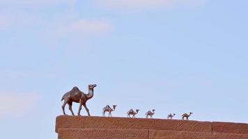 Petra, Jordan, 2022 - Various size camel metal figures stand in caravan on stairs by souvenir shop