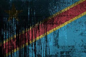 Democratic Republic of the Congo flag depicted in paint colors on old and dirty oil barrel wall closeup. Textured banner on rough background photo