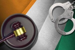 Ivory Coast flag with judge mallet and handcuffs in dark room. Concept of criminal and punishment, background for judgement topics photo
