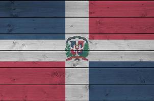 Dominican Republic flag depicted in bright paint colors on old wooden wall. Textured banner on rough background photo