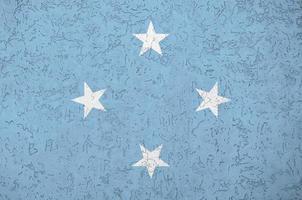 Micronesia flag depicted in bright paint colors on old relief plastering wall. Textured banner on rough background photo