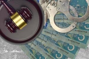 5 Canadian dollars bills and judge hammer with police handcuffs on court desk. Concept of judicial trial or bribery. Tax avoidance