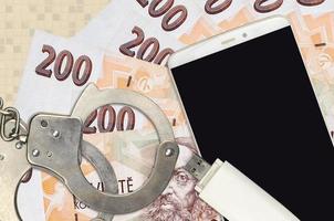 Billetes de 200 korun checos y smartphone con esposas policiales. concepto de ataques de phishing de piratas informáticos, estafa ilegal o distribución blanda de malware foto