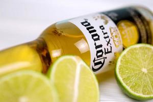 KHARKOV, UKRAINE - DECEMBER 9, 2020 Bottle of Corona Extra Beer with lime slices. Corona produced by Grupo Modelo with Anheuser Busch InBev most popular imported beer in the US photo