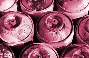 A lot of used metal tanks with paint for drawing graffiti Image toned in Viva Magenta, color of the 2023 year photo