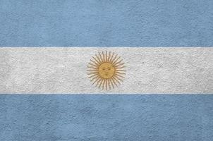 Argentina flag depicted in bright paint colors on old relief plastering wall. Textured banner on rough background photo