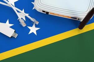 Solomon Islands flag depicted on table with internet rj45 cable, wireless usb wifi adapter and router. Internet connection concept photo