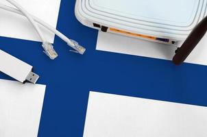 Finland flag depicted on table with internet rj45 cable, wireless usb wifi adapter and router. Internet connection concept