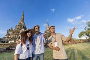 Thai local tour guide is explaining the history of old Siam to the couple of tourist on their backpacker honeymoon travel to Ayutthaya, Thailand photo