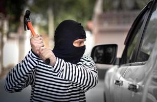 ladrón de autos secuestra y roba o roba dinero en autos y autos rompiendo la ventana de la puerta sin alarma de auto trabajo criminal ilegal y violento foto