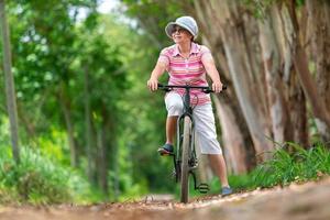 senior business woman, female, ride or bike mountain bicycle in country park near home town for healthy exercise in summer weekend photo