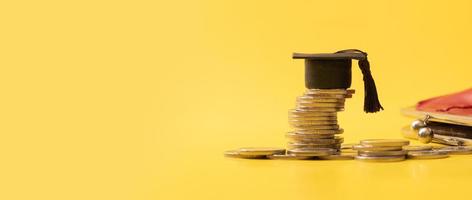 Banner with graduated cap with coins on yellow background. Savings for education concept photo