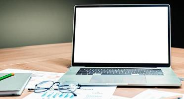 Mock up white screen on display laptop with glasses and notebook on table in meeting room photo