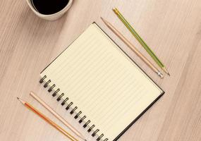 Top view notebook, pencil and coffee cup on table photo