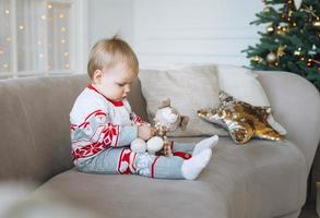 linda niñita en invierno en general en la habitación con árbol de navidad en casa, feliz año nuevo foto