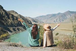 Young women travellers friends on background of the turquoise Katun river, Altai mountains photo